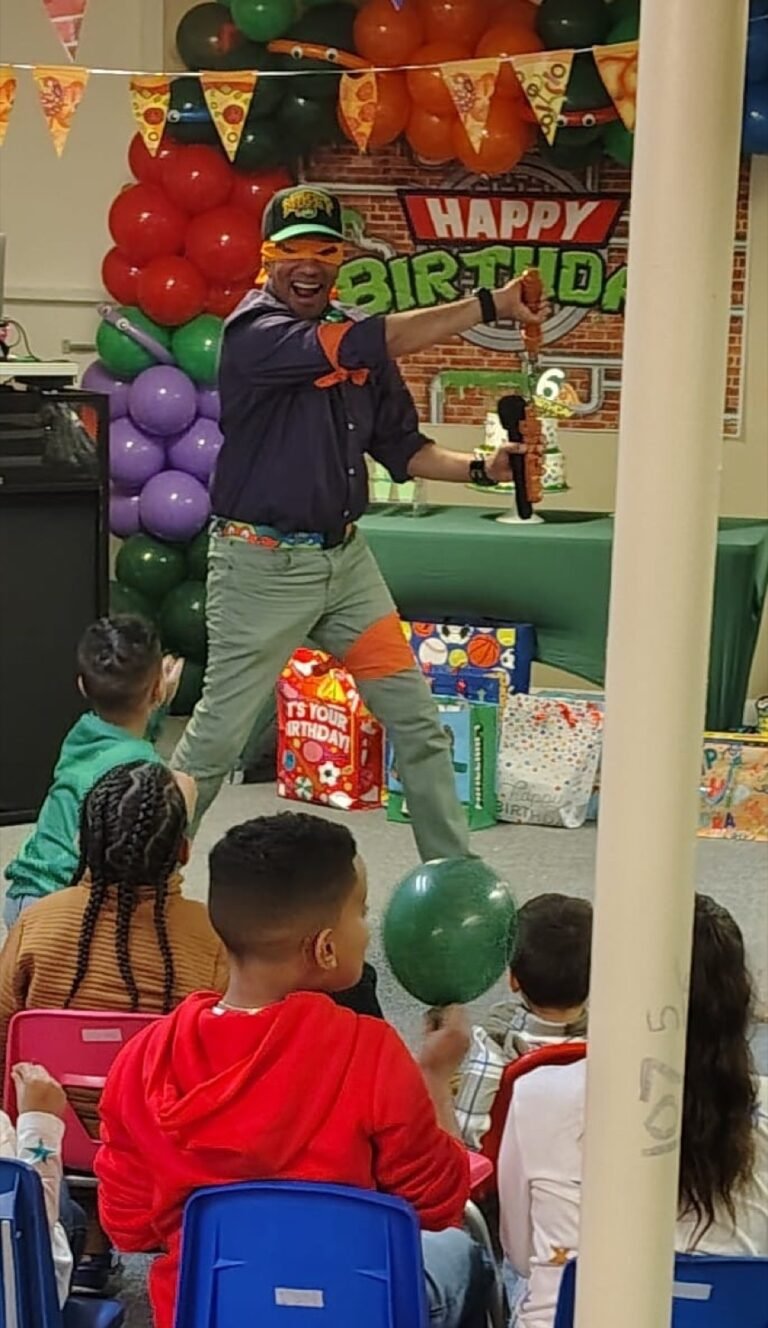 Uncle Raf leading a kids show in front of a balloon backdrop